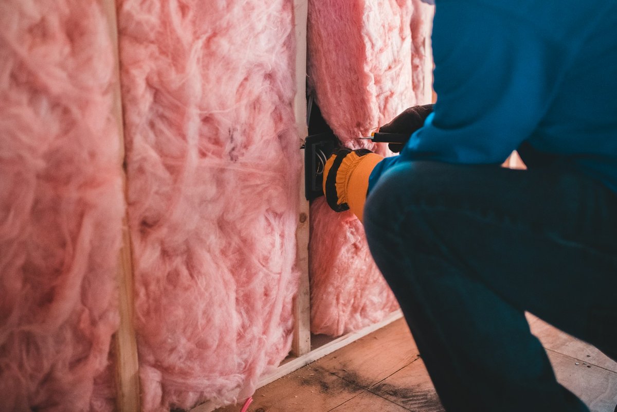 An electrical box being fitted into an insulated wall during interior work